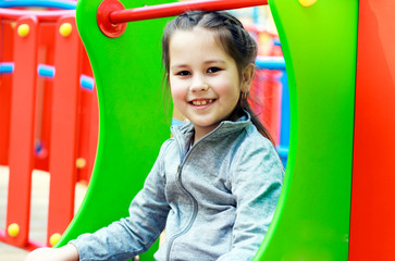 Fototapeta na wymiar little smiling girl drives down a slide on the playground