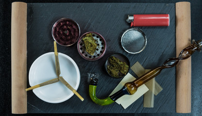 Marijuana joints lie in the ashtray. Smoking pipe, grinder, cannabis.