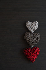 Red, grey and white wicker hearts on wooden background