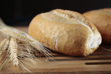 Pão francês rústico em base de madeira com trigo