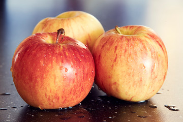 Three red apples on dark background