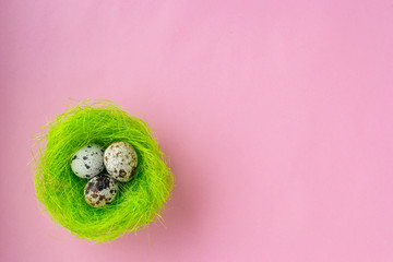 Easter eggs in green nest on pink background.