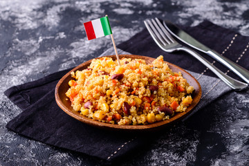 Quinoa dish with vegetable and cherry tomatoes, chopping board