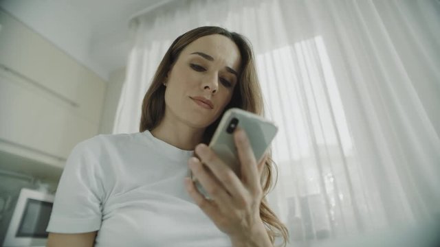 Young woman using mobile phone at home. Close up of girl using smartphone