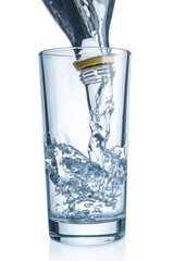 Flowing pure water from bottle into glass on white background