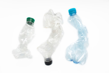 Flattened empty used plastic PVC bottles on white background. Crumpled bottle - recycle eco concept.