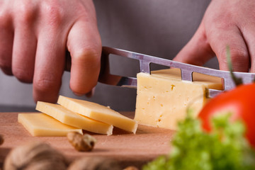 young woman slicing cheese in a gray apron