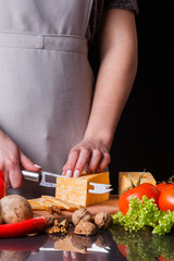 young woman slicing cheese in a gray apron