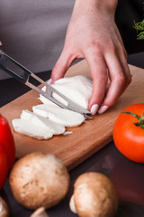 young woman slicing cheese in a gray apron
