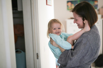 Loving young mom smiling embracing cute daughter