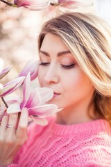 Portrait of a beautiful young woman near a magnolia. Spring.