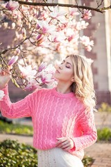 Portrait of a beautiful young woman near a magnolia. Spring.