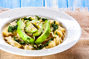 Pasta with avocado on wooden table