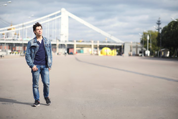 A young man walks in the park at lunch time. A man is on a walk in the city. A student in the park.