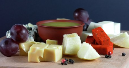 Cheese plate close-up with several varieties of fruit and honey cheese.