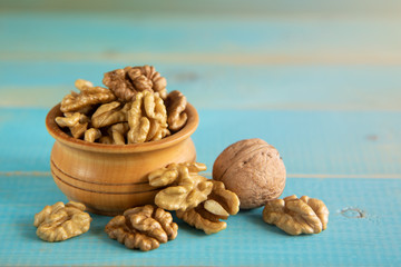Walnuts on blue rustic table in wooden bowl