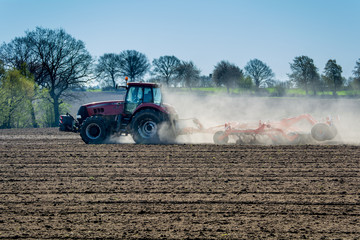 Traktor pflügt staubiges Feld im Frühjahr