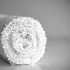 White clean, new terry towel twisted into a roll. Spa background in light. Clean white towel rolled...