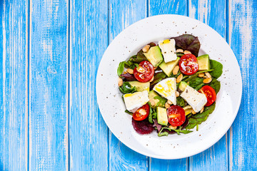Salad with avocado and cheese on wooden background