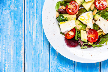 Salad with avocado and cheese on wooden background