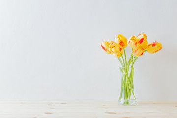 Home interior with decor elements. Yellow tulips in a glass vase on a wooden table