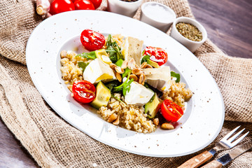 Salad with avocado and cheese on wooden background