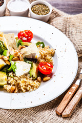 Salad with avocado and cheese on wooden background