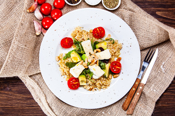 Salad with avocado and cheese on wooden background