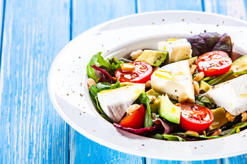 Salad with avocado and cheese on wooden background