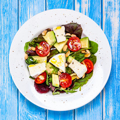 Salad with avocado and cheese on wooden background