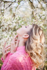 Spring portrait of a young blonde near a flowering tree. Happy young woman.