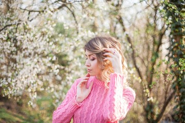 Spring portrait of a young blonde near a flowering tree. Happy young woman.