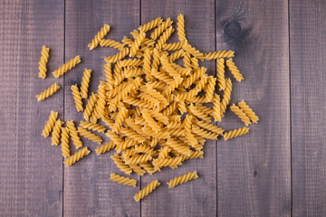 Fusilli Italian pasta uncooked noodles on wooden background.