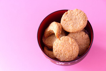 Homemade gluten free oatmeal cookies in bowl. Selective focus. Pink background.