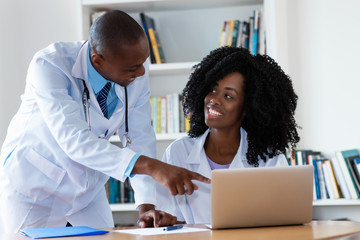 African american male doctor and nurse working at computer