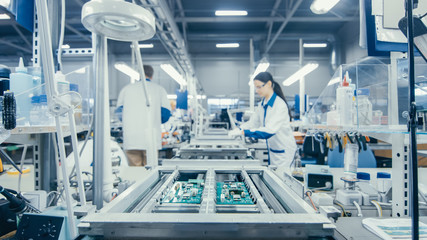 Shot of an Electronics Factory Workers Assembling Circuit Boards by Hand While it Stands on the...