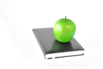 green apple standing on a notebook or book on a white background