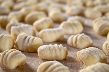 Fototapeta na wymiar Italian food speciality: hand made potato gnocchi on a wooden board, ready to be cooked. Home made and hand rolled on a fork. Close up, selective focus.