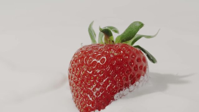 Straberry falls into milk, slow motion close-up. Shot on Red