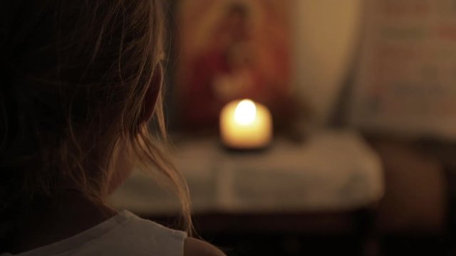 Pri&egrave;re d'une petite fille devant une bougie, une ic&ocirc;ne et rameaux