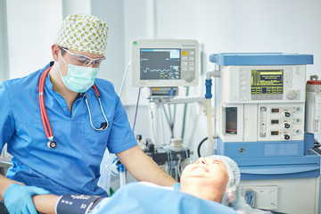 Several doctors surrounding patient on operation table during their work. Team surgeons at work in...