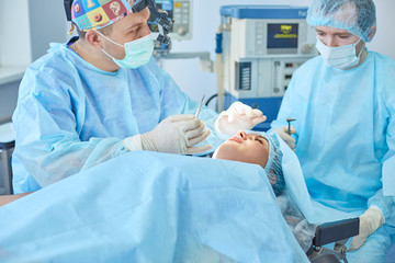 Several doctors surrounding patient on operation table during their work. Team surgeons at work in operating room