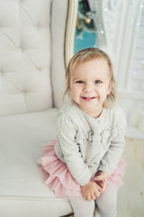 cute little child sitting in chair near Christmas tree. Happy new year. Portrait little girl. Christmas concept.