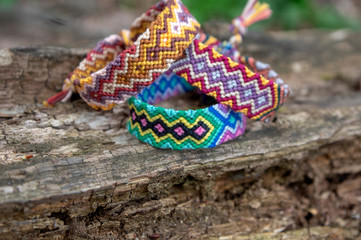 Group of colorful handmade homemade natural woven bracelets of friendship on old wood background, checkered patterns