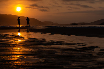Silhouettes of people on the background of a golden dawn on the beach of Sanya, Hainan Island, China