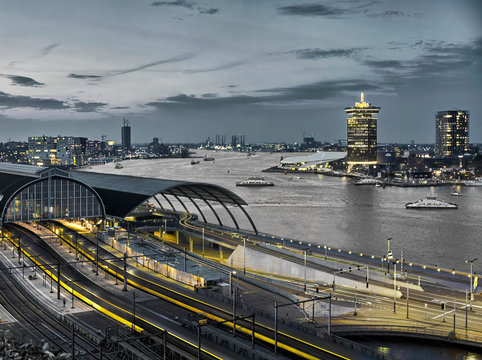 Black and white image of Amsterdam city center with central station, modern architecture and river  with yellow accents