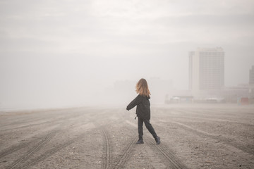 Girl on walking on the beach during fog at atlantic city shore