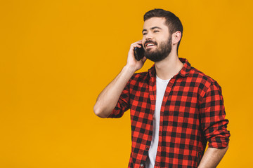 Happy smiling young man talking on mobile isolated on yellow background.
