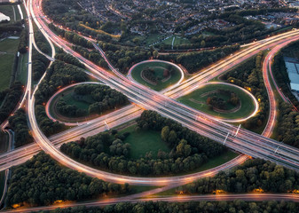 Aerial long exposure of highway node with overpasses and curves illuminated by car lights during...