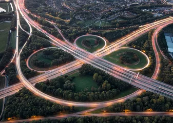 Fototapeten Aerial long exposure of highway node with overpasses and curves illuminated by car lights during rush hour traffic  © Donald